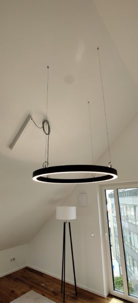 Große runde LED-Pendelleuchte mit Lichtschiene im Dachgeschoss, installiert von SHI Gebäudetechnik.