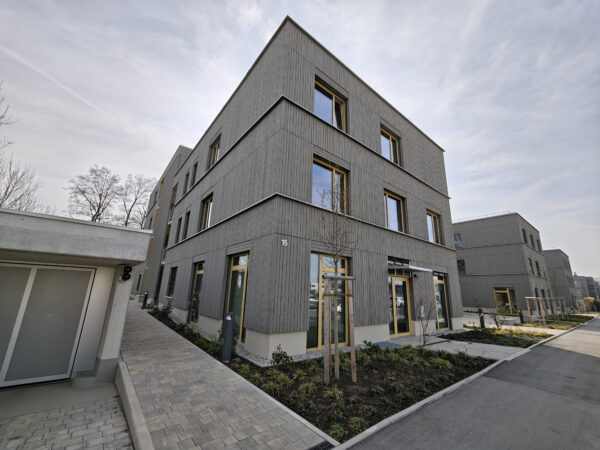 Vorderansicht einer Wohnanlage mit grauer Fassade und Tiefgarage