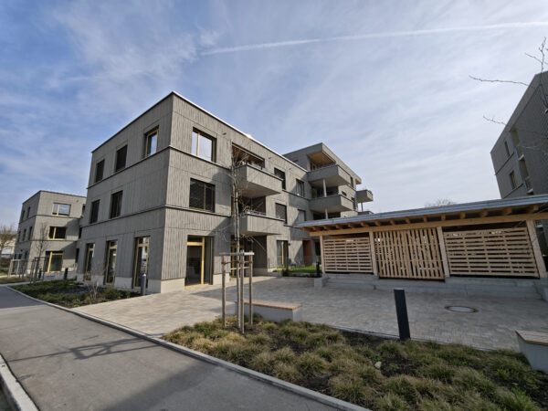 Wohnanlage Sheridan Park & Junia GbR mit grauer Fassade, Balkonen und begrüntem Innenhof