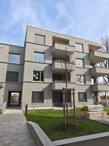Wohnanlage Sheridan Park & Junia GbR mit grauer Fassade, Balkonen und begrüntem Innenbereich