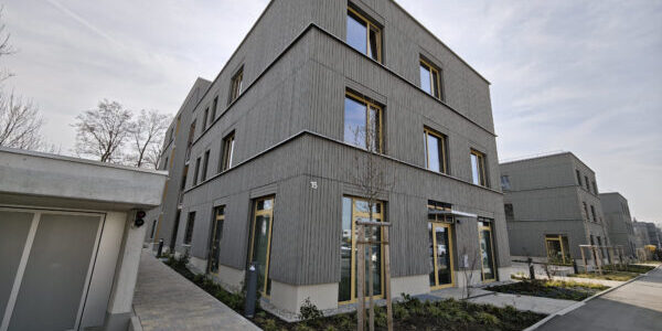 Vorderansicht einer Wohnanlage mit grauer Fassade und Tiefgarage